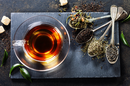 Tea composition with old spoon on dark background