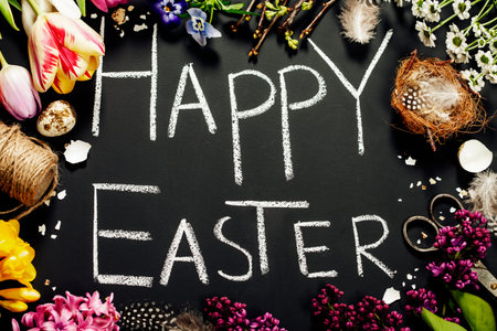 Easter greetings on a blackboard with eggs, flowers and nest