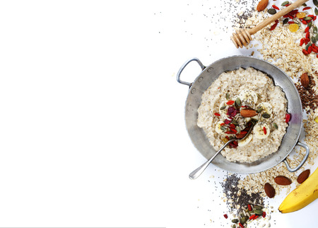 Healthy breakfast. Home made oatmeal porridge, goji berries, pumpkin and chia seeds  in a ceramic bowl on white background.の写真素材