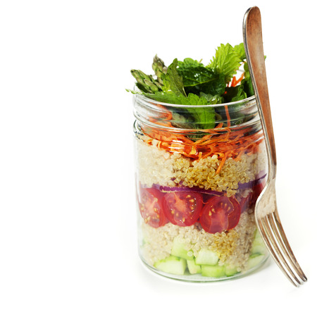 Cucumber, quinoa, tomato, onion, carrot and mint salad in a jar over whiteの写真素材