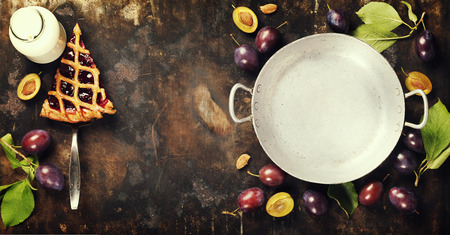 overhead view of fresh plum pie or tart and plums on dark rustic backgroundの写真素材