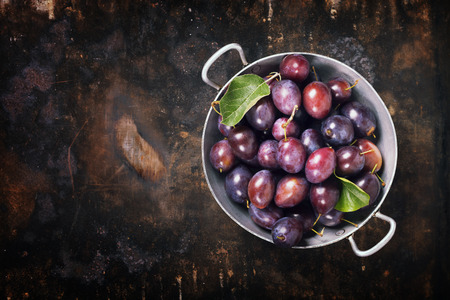 Plums in a bowl on a rural background. Fresh bio fruitsの写真素材