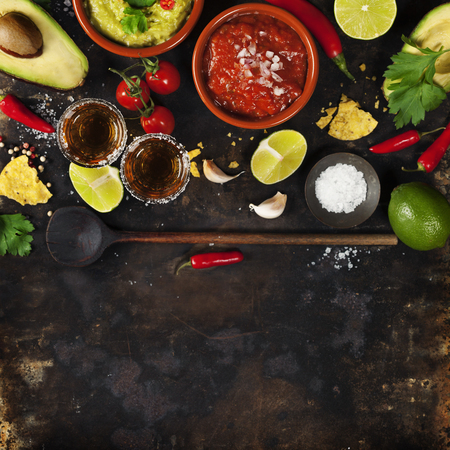 Mixed mexican food background. Party food. Guacamole,nachos, salsa, peppers, tomatoes, avocado and tequila shots on a rustic table. Space for text. Top view. Tex-mex cuisine. Assorted appetizers. Food frameの写真素材