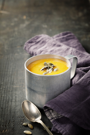 Pumpkin soup in a metal pot on a wooden surfaceの写真素材
