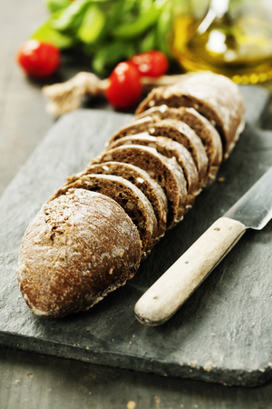 Sliced rye bread on cutting board and ingredients for making sandwichesの写真素材