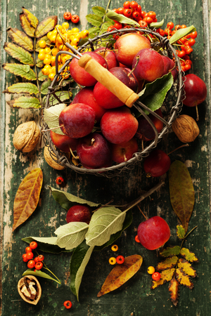 Apples in basket and autumn decorations on old wooden backgroundの写真素材