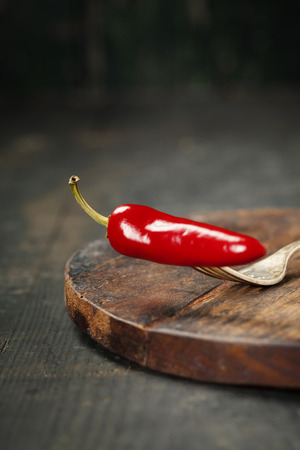 Hot chilli pepper on fork. Wooden backgroundの写真素材