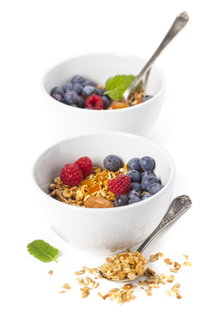 Healthy breakfast. Granola with fresh organic raspberries and blueberries on white backgroundの写真素材