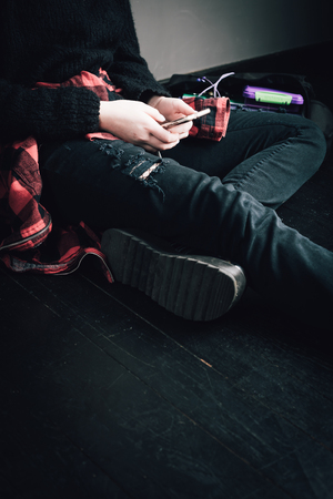 Young alternative girl sitting on the black floor with a schoolの写真素材