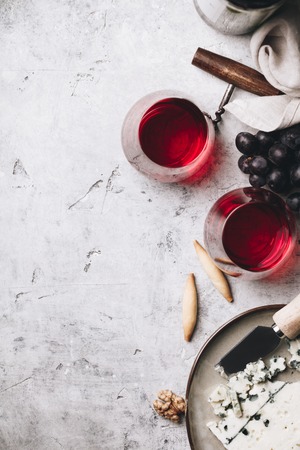 Glasses of red wine, cheese and grapes on rustic concrete backgrの写真素材