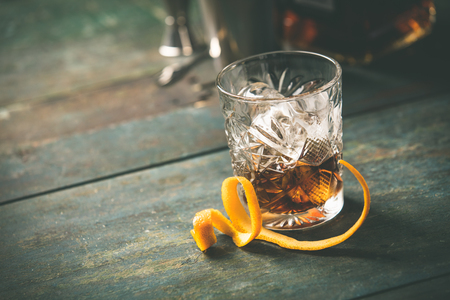 Alcoholic cocktail  with orange peel and ice on wooden tableの写真素材