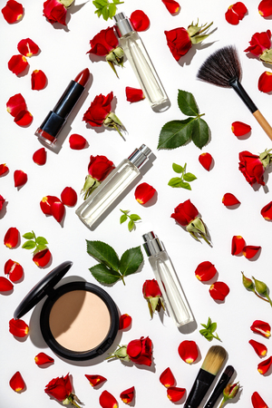 Bottles of woman perfume with cosmetic products and red roses on white backgroundの写真素材
