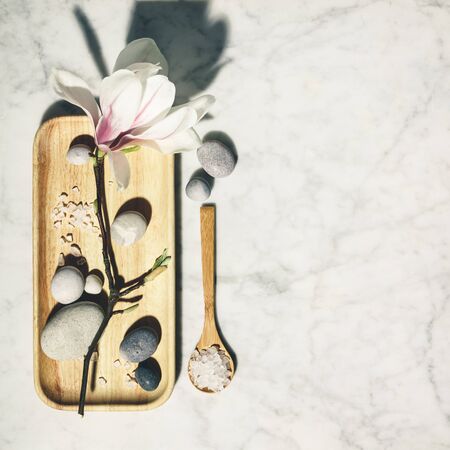 Flat lay composition with beautiful spring magnolia flowers and grey stones on white marble background. Relaxation and zen like concept.の写真素材