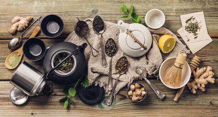 Various tea and teapots composition, dried herbal, green, black tea and matcha tea on wooden table background, flat layの写真素材