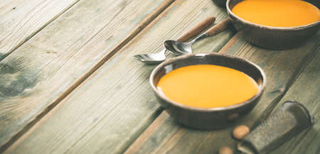 Pumpkin soup in bowls on wooden table, space for textの写真素材