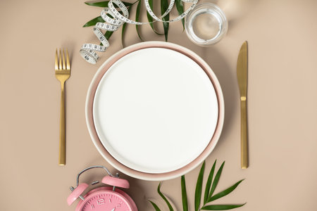 Composition with cutlery, empty plate, measuring tape and alarm clock on color background. Diet...