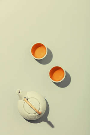 Tea concept, two white cups of tea and teapot on concrete backgroundの写真素材