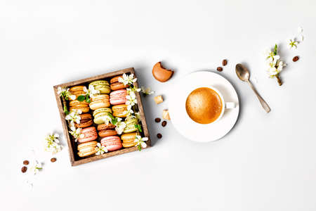 Macaroons in wooden box with spring flowers and cup of coffeeの写真素材