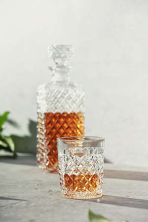 Glass of whiskey with ice cubes and carafe close upの写真素材