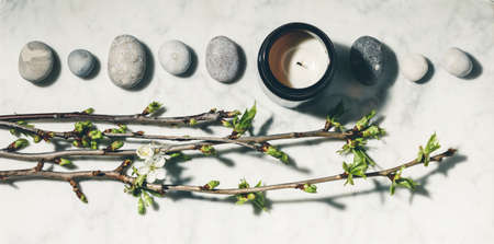 Flat lay composition with beautiful spring cherry branches, natural candle and grey stonesの写真素材