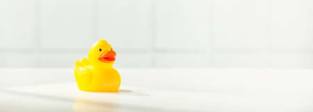 Cute rubber duck on white bathroom countertop with space for textの写真素材