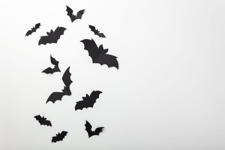 halloween and decoration concept - black paper bats flying over white background