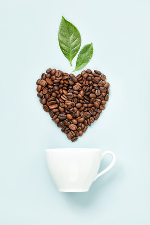 White coffee cup and coffee leaves and beans in shape of heart on blue background, flat layの写真素材