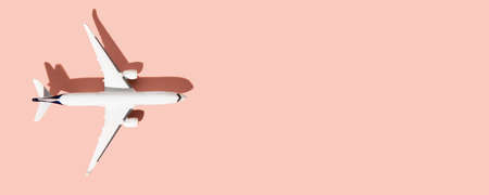 Miniature white airplane on a pink background. Horizontal photo, banner, flat lay. Space for text, copy space. Concept - air travel, ticket bookingの写真素材