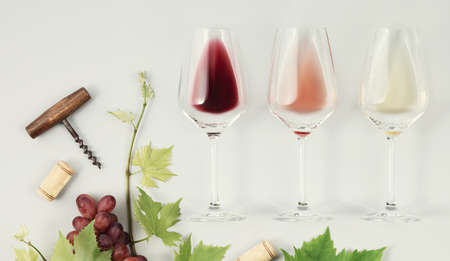 Flat-lay of red, rose and white wine in glasses on white backgroundの写真素材