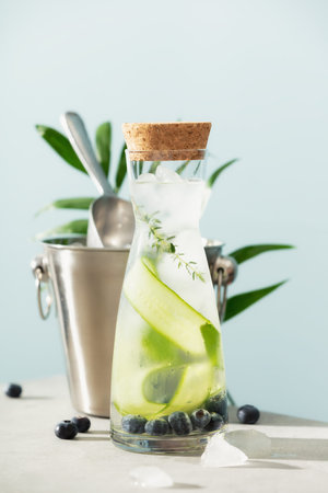 Summer infused water with cucumber,  and rosemary and ice bucket on blue sky background, Summer sea...