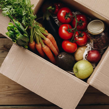 Food selection in paper box: fruit, vegetable, herbs, legumes, cereals, leaf vegetable on wooden background.の写真素材