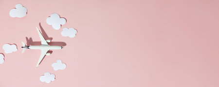 Miniature toy airplane and paper clouds on colorful background. Flat lay design of travel concept
