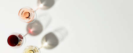 Flat-lay of red, rose and white wine in glasses on white background, banner, copy spaceの写真素材