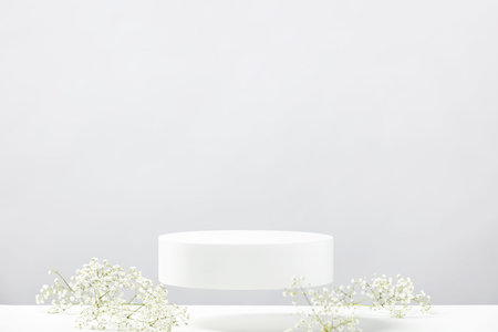 Flying empty white podium and white flowers on grey background. Mock up stand for product...