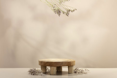 Empty round wooden podium for product presentation and dry leaves on beige background for cosmetic product mockupの写真素材