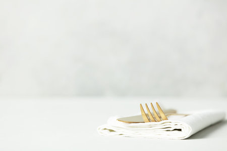 Golden Cutlery set and white napkin on light grey table with space for textの写真素材