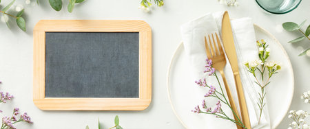 Gold Cutlery with chalk board, eucalyptus branches on white plate with napkin over light grey Background. Minimalistic design. Copy Space bannerの写真素材