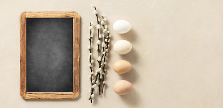 Easter composition with vintage Easter decorations and chalk board on beige stone backgroundの写真素材