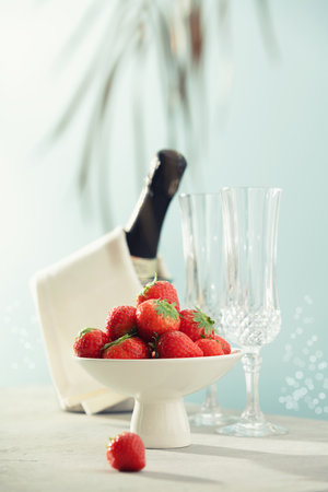 Bottle of champagne, two glasses and strawberries on sea and sky background.の写真素材