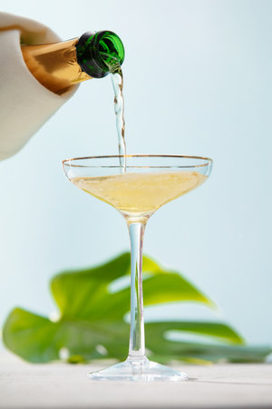 Pouring champagne into glass on blue sky backgroundの写真素材