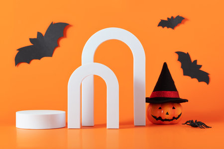 Creative Halloween composition with pumpkin, spiders, white podium and orange background. Modern Halloween aesthetic.の写真素材