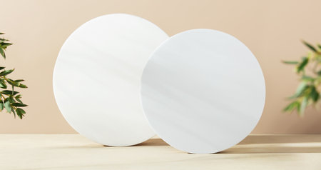 White foam circle shaped pedestals and eucalyptus branches on beige table with copy space, side view. Podium mockup background for products. Advertising template. Foam platform. Abstract geometric pedestal.の写真素材