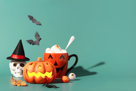 Happy halloween holiday concept. Halloween decorations, bats, ghosts, spiders, pumpkins, skull, cup of Chocolate with marshmallow on blue background. Halloween party poster mockup with copy space.の写真素材