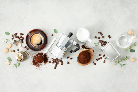 Moka pot, espresso cup, ground coffee, milk, sugar and coffee beans on a grey concrete backgroundの写真素材