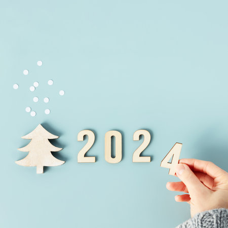 Close up image of hand folds wooden numbers into the number of the new year 2024の写真素材