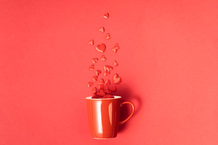 Valentines day concept. Red cup with roses, chocolate and red hearts on red backgroundの写真素材