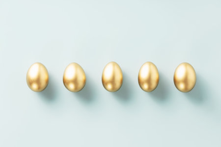 a row of golden eggs on a blue background top view flat layの写真素材