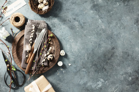 Easter table setting with spring flowers and cutlery on dark blue background top view flat layの写真素材
