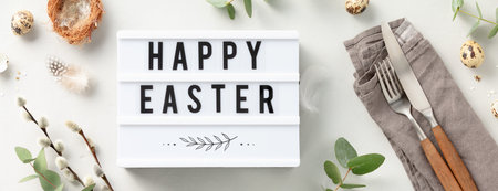 lightbox text Happy Easter, table setting, easter eggs and spring branches on light grey background