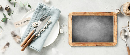 plate with a linen napkin, knife, fork, chalkboard, Easter eggs and feathersの写真素材